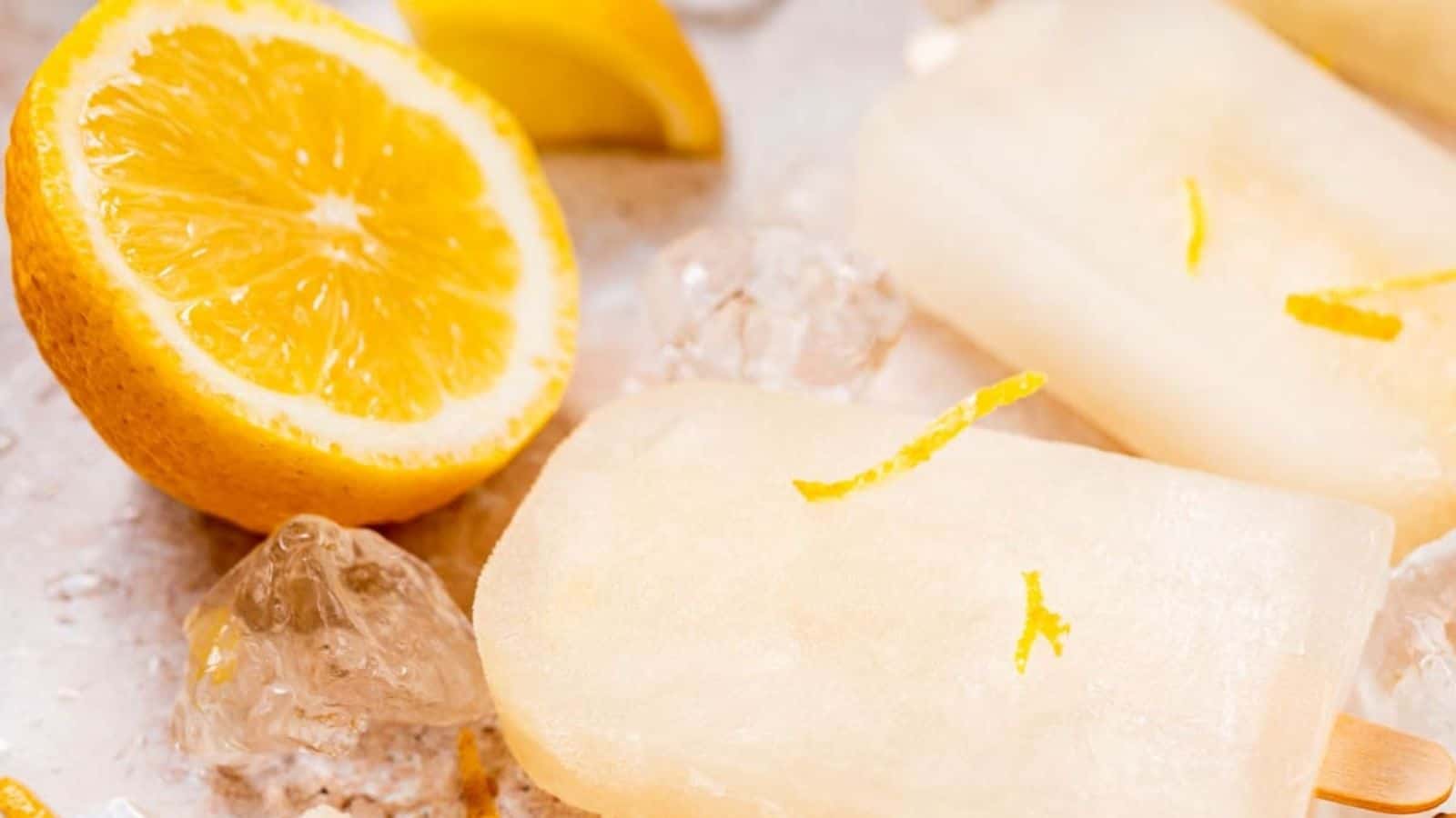A close-up image of lemonade popsicles with a half of lemon on the side.