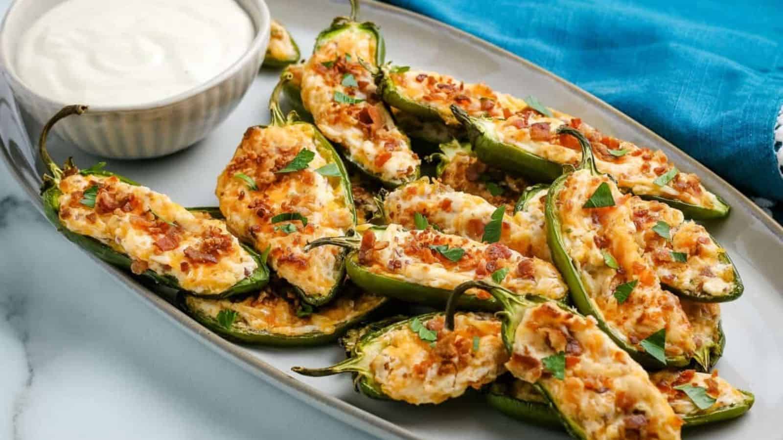 Jalapeño Poppers on a platter with a bowl of dipping sauce.