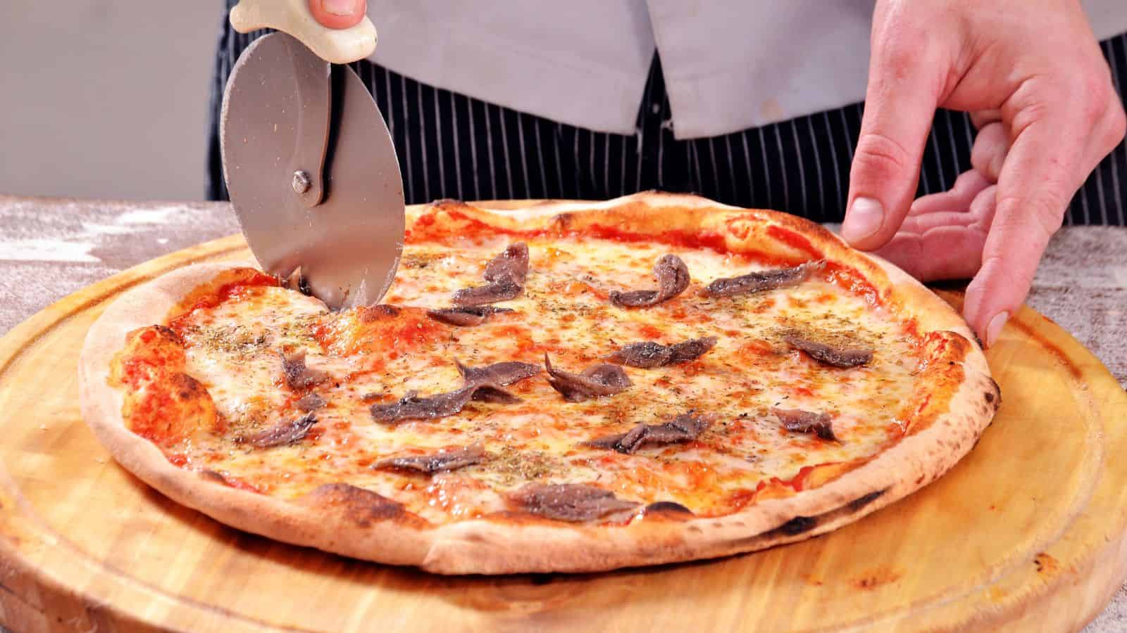 Cutting anchovy pizza.
