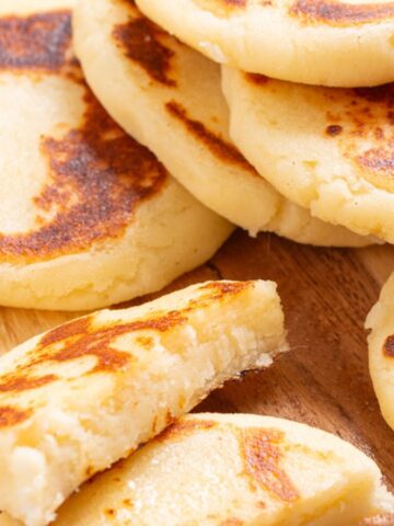 Close up of arepas con queso on a wooden board.