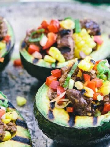 Close-up image of asian steak stuffed grilled avocados on a plate.