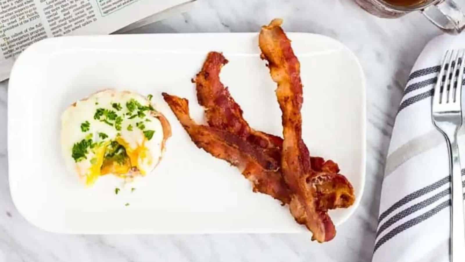 Bacon and eggs on a plate with a cup of coffee.