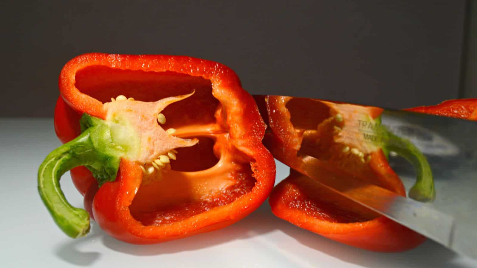 Red bell pepper cut in half with a knife.