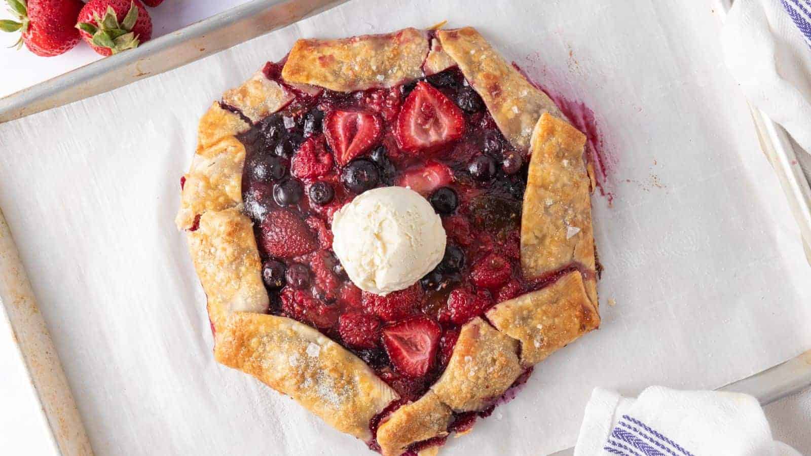 A top view image of mixed berry galette in sheet pan with a scoop of icecream in the middle.