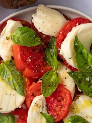 An overhead photo of caprese salad served in a white bowl.