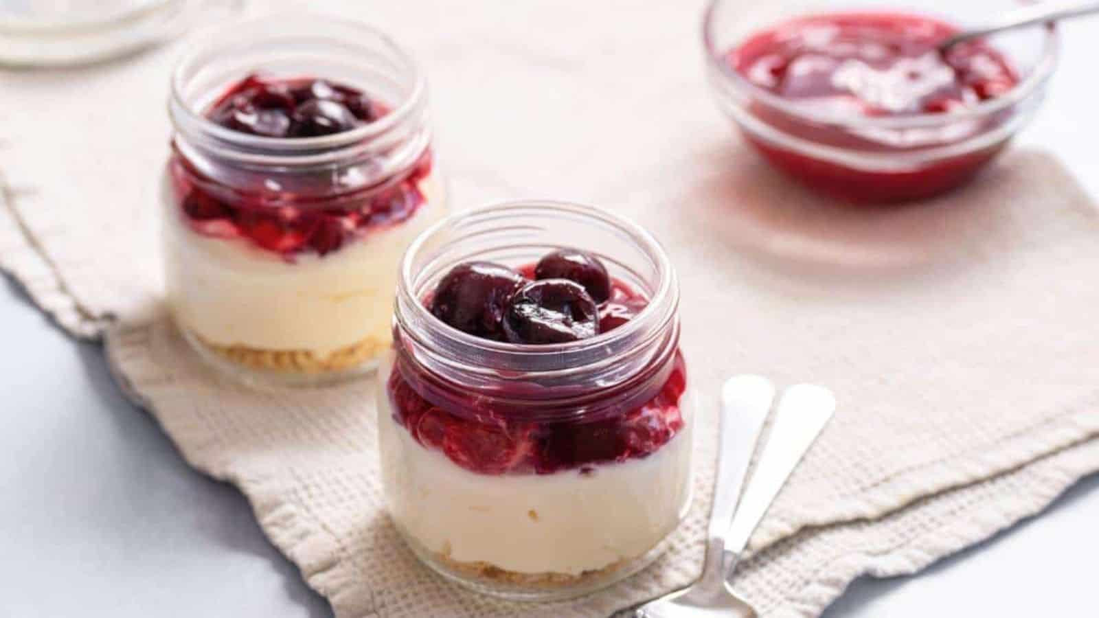Cheesecakes in jars with cherry topping.