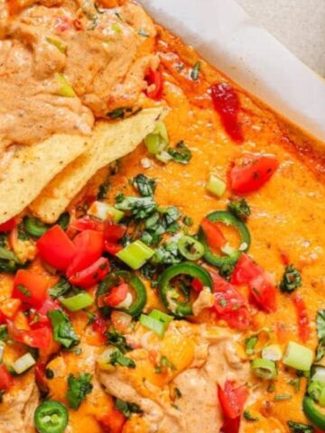 Overhead view of chili cheese dip in a white pan with some chips dipped in it.