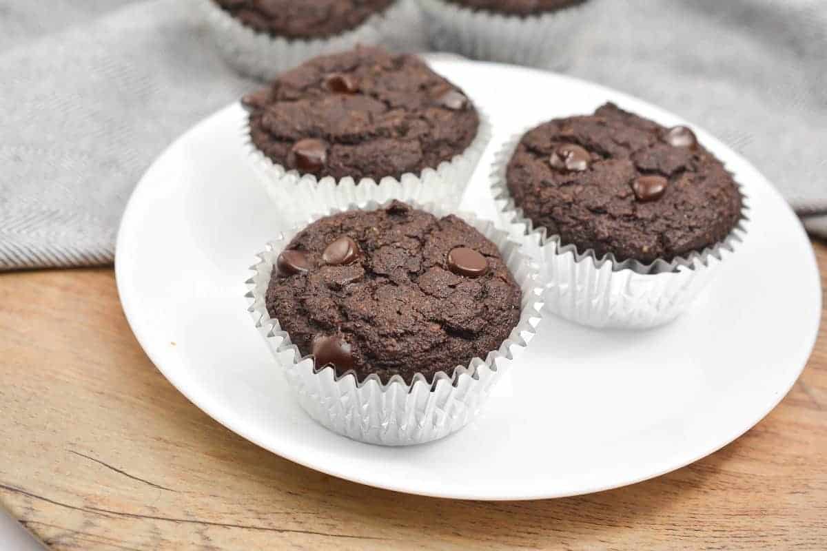 Three chocolate muffins on a white plate.