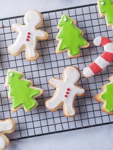 Overhead view of Christmas sugar cookies on a white plate, with cookies on the side as well.