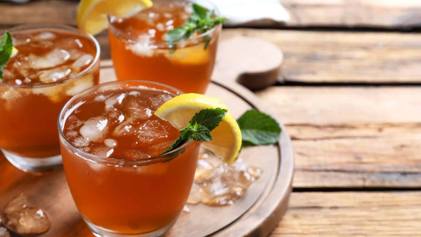 Three glasses of iced tea in a wooden tray.