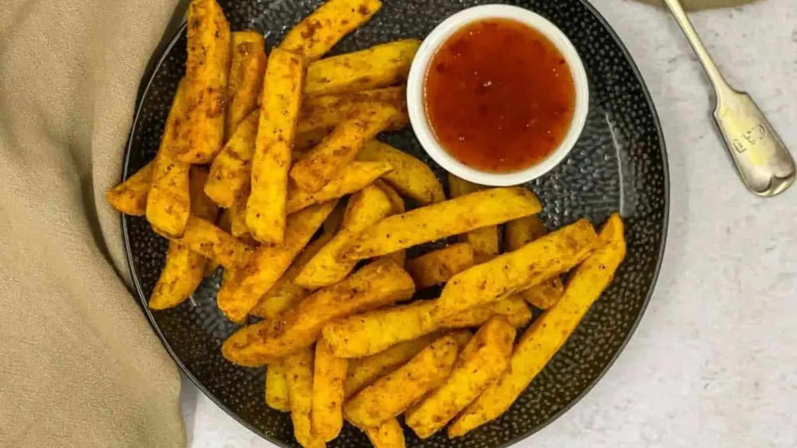 Top view of masala fries and dip in a black plate.