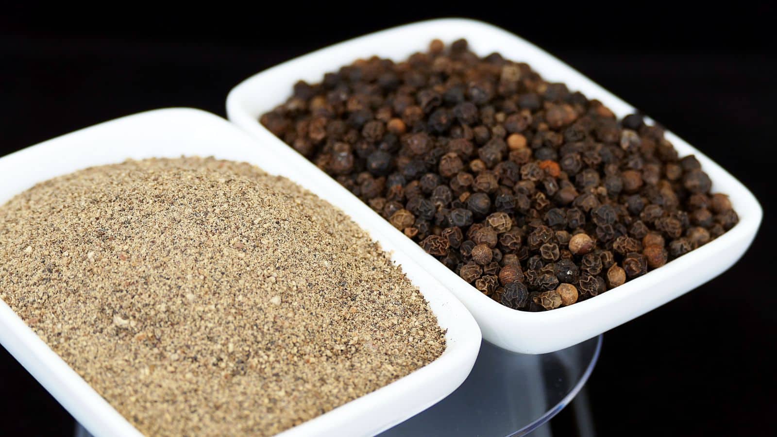 Close-up of ground and pre ground black pepper side by side.