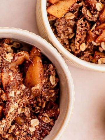 Overhead view of two bowls of gluten-free apple crisp with green apples in the background.