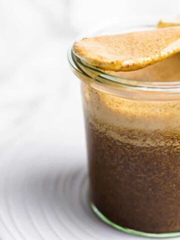 A jar of Worcestershire Sauce on a plate with a spoon.