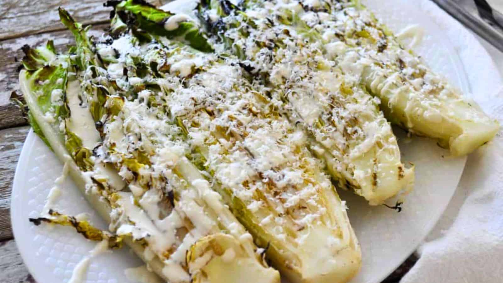 Close-up of grilled romaine with truffle dressing on a white plate.