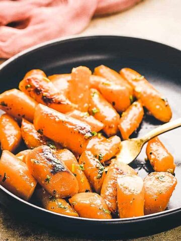 Honey garlic carrots in a black dish.