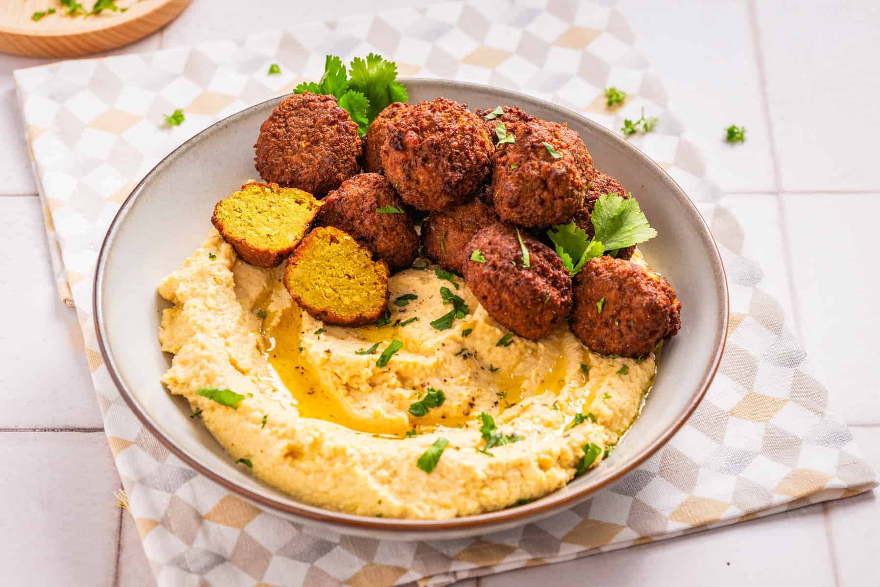 A close up image of falafels on a bowl of hummus.