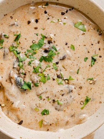 A bowl of Hungarian mushroom soup with a gold spoon.