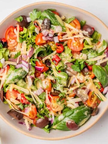 Italian chopped salad in a bowl next to dressing.