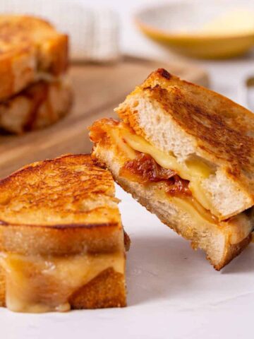 An image of a sliced kimchi grilled cheese sandwich resting on the other slice.