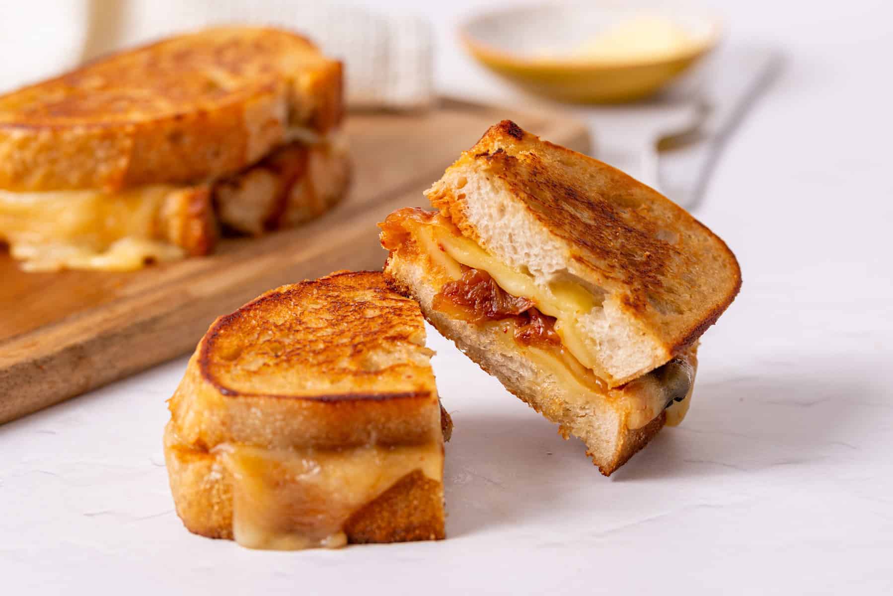 An image of a sliced kimchi grilled cheese sandwich resting on the other slice.