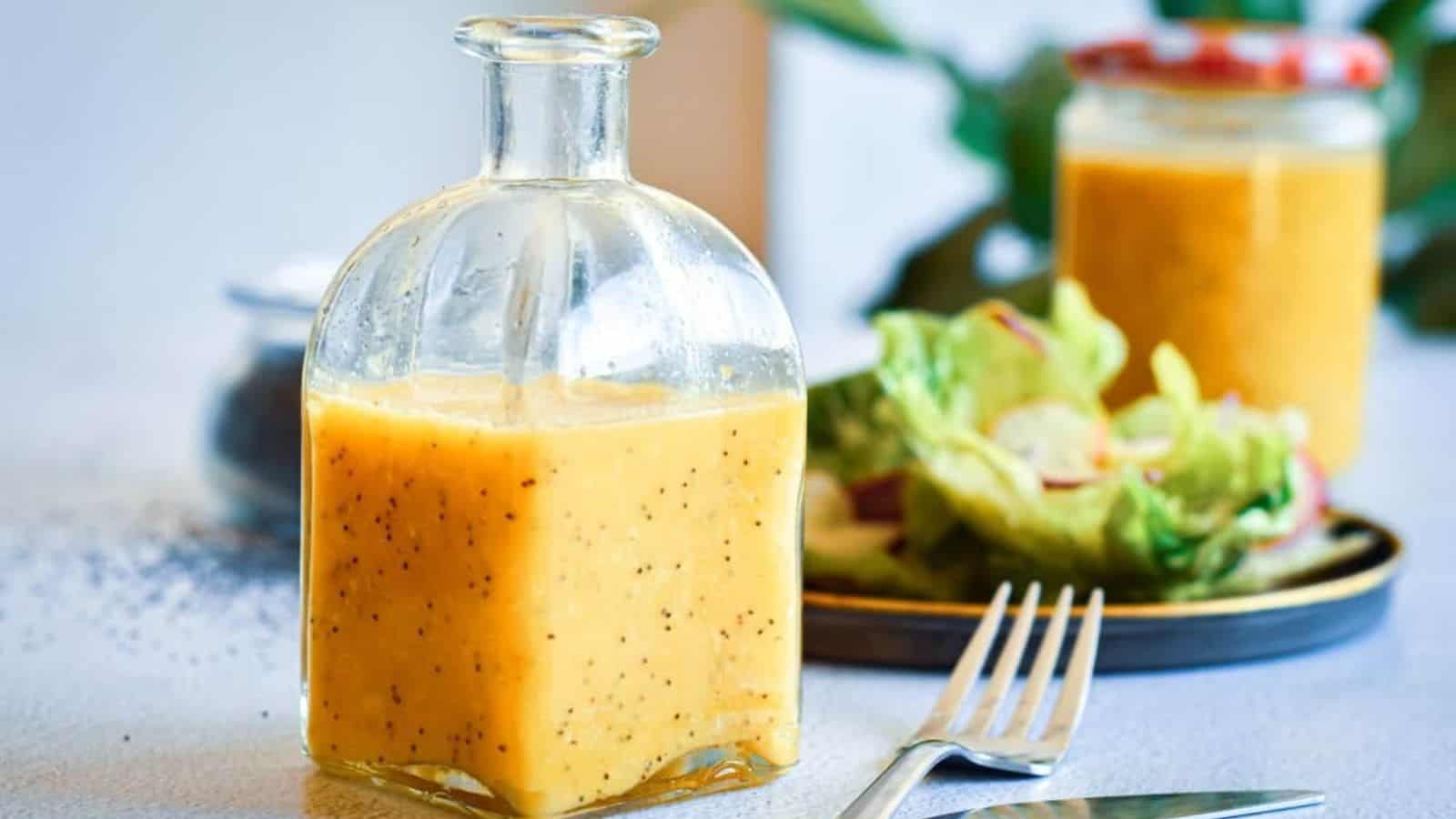 A jar of dressing next to a salad and fork.