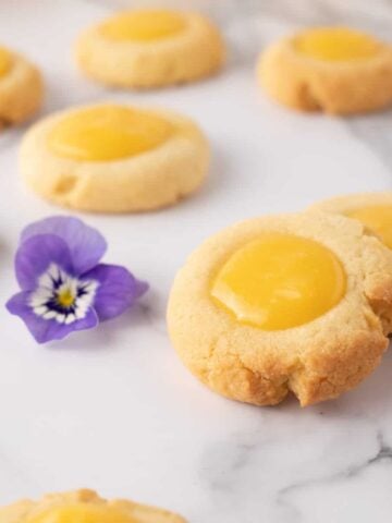 Close up view of lemon curd cookies with a lavender flower in background.
