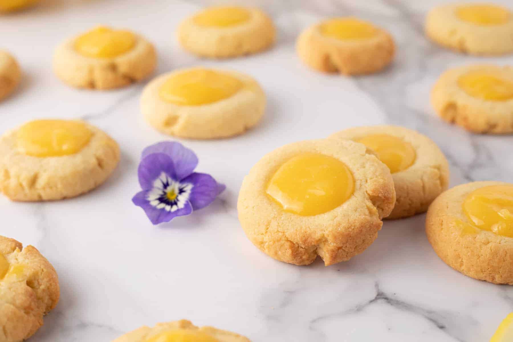 Close up view of lemon curd cookies with a lavender flower in background.