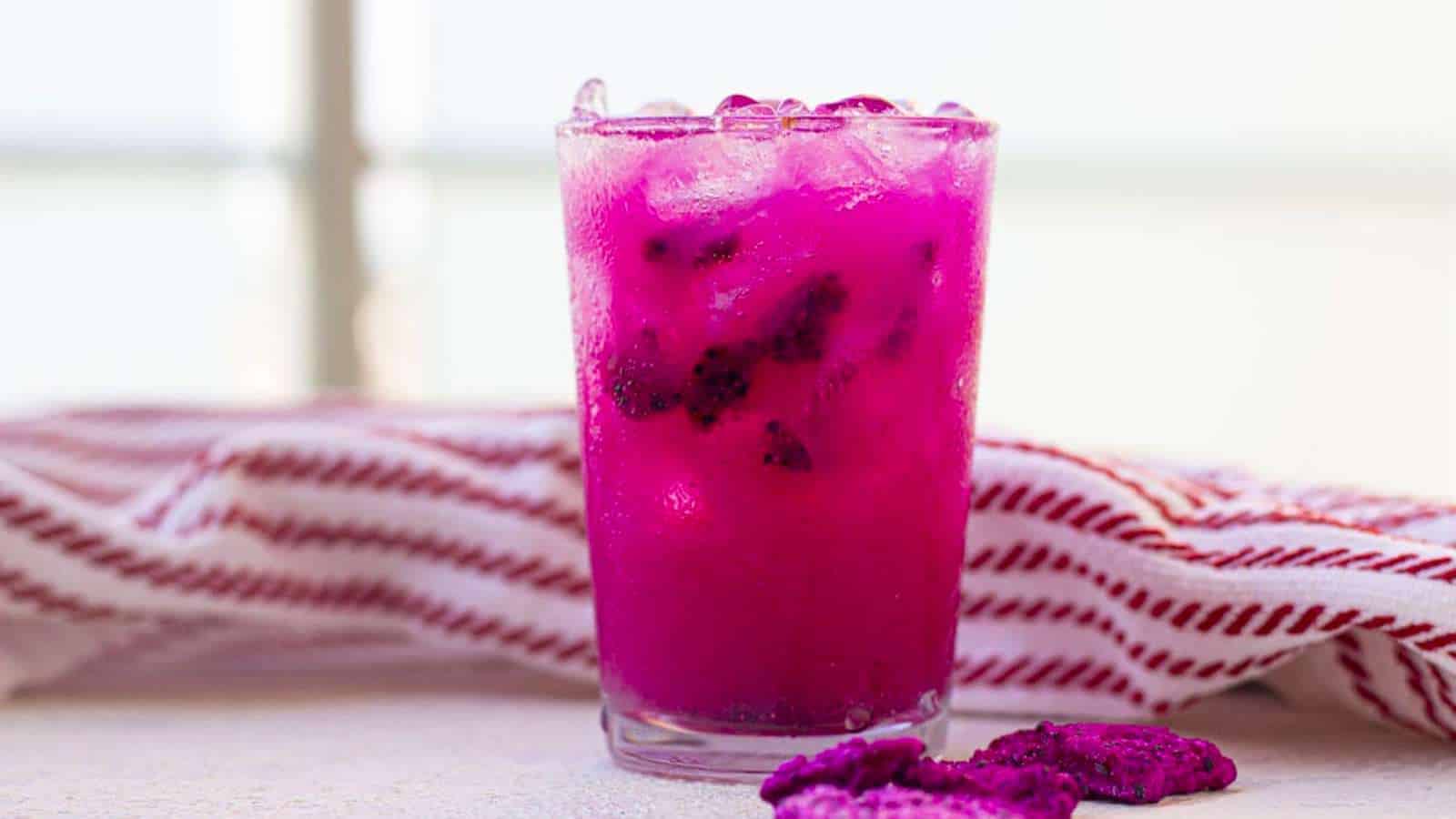 A pink drink with ice, berries, and a table.