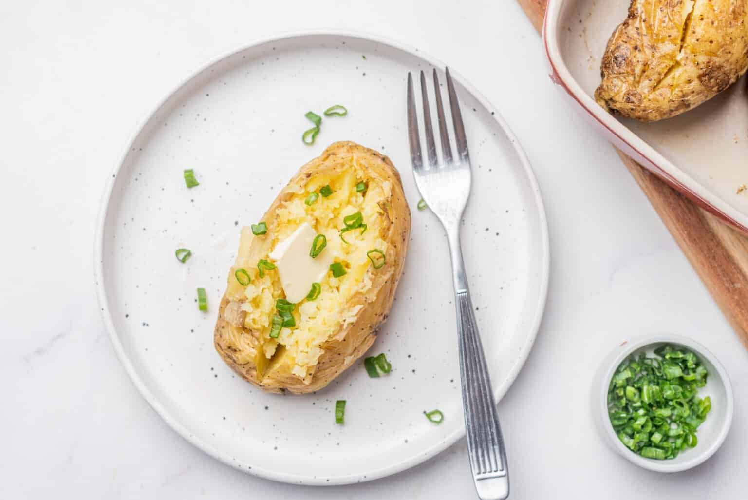 An overhead image of microwave baked potato on a plate with a fork.