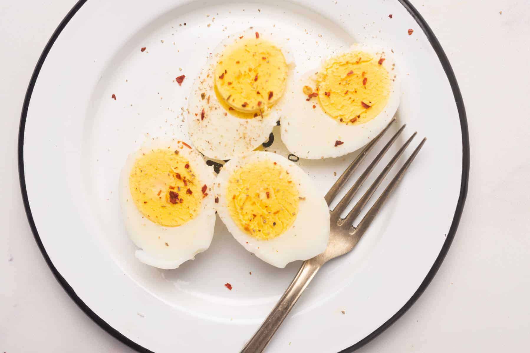 Overhead view of hard boiled eggs on a white plate.