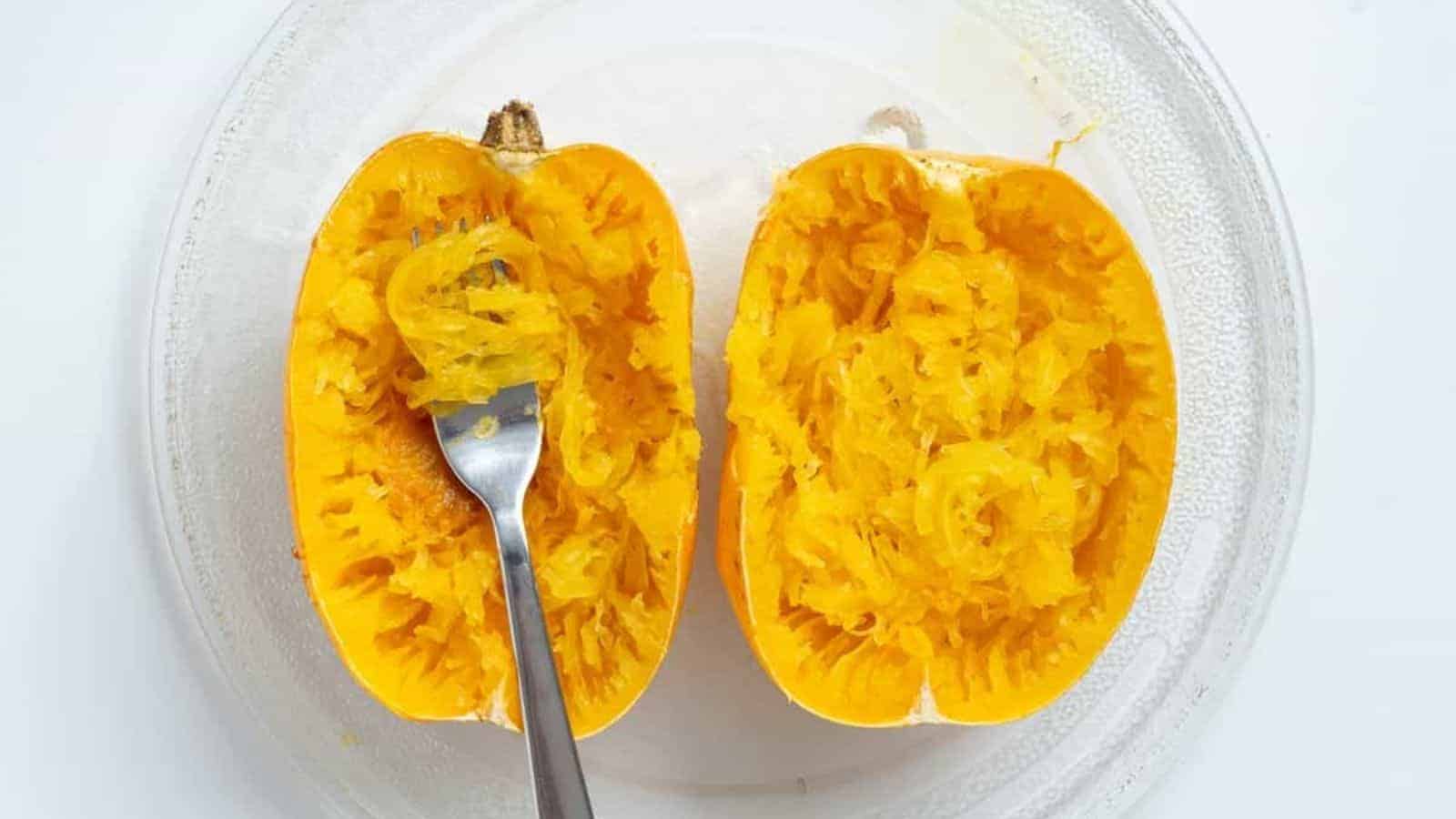 An image of spaghetti squash cut in half on a clear glass plate.