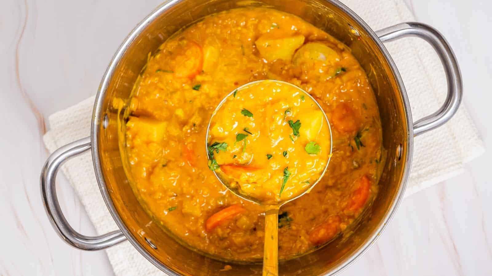 An overhead image of mulligatawny soup being scooped out in a large pot.