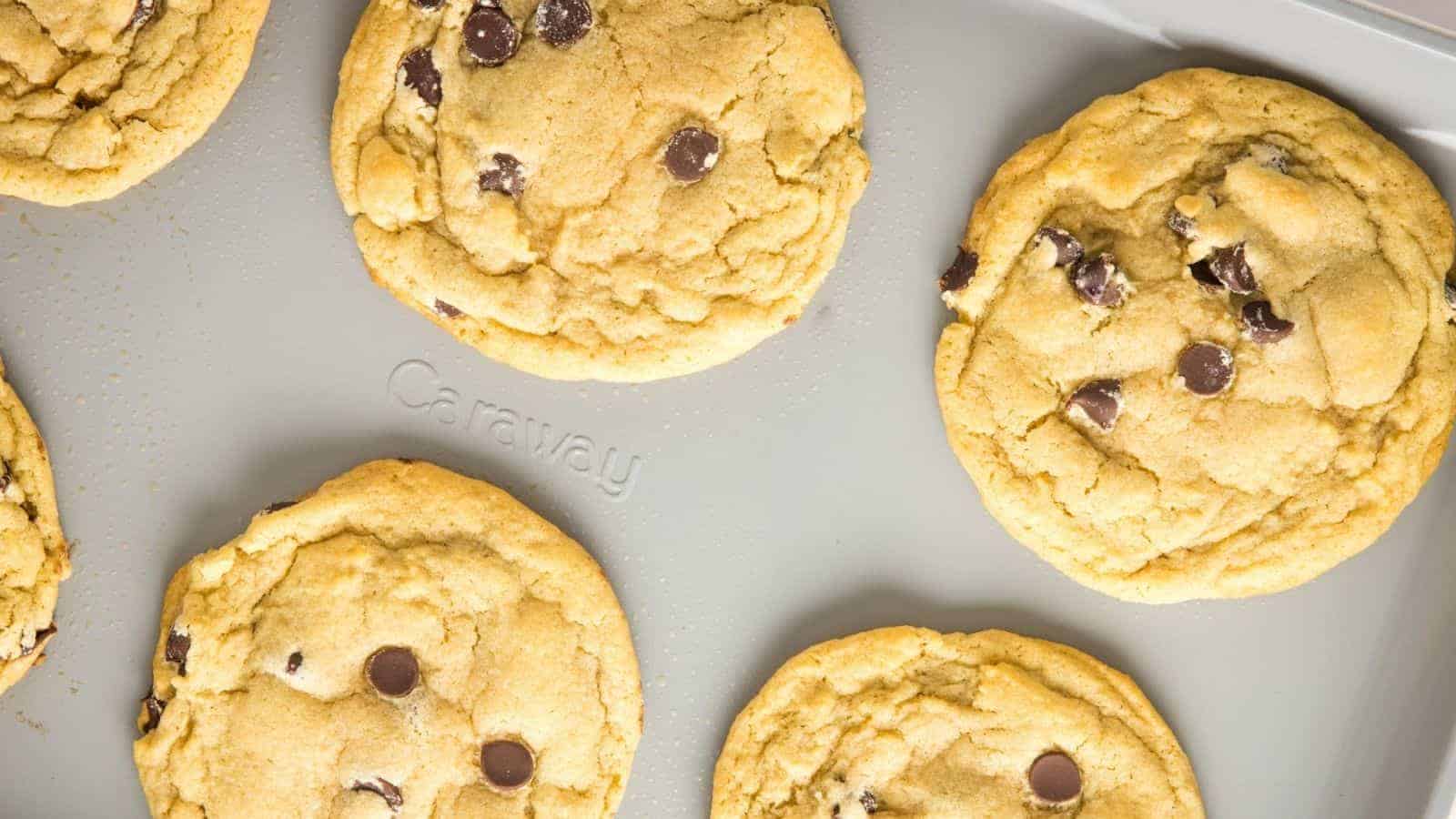 A close-up image of freshly baked chocolate chip cookies on a baking sheet.