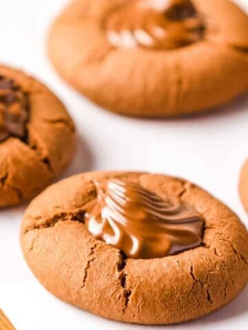 Side angle view of piped Nutella cookies on a wooden board lined with parchment paper.