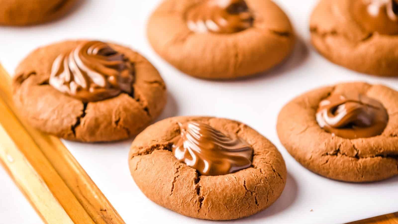 Side angle view of piped Nutella cookies on a wooden board lined with parchment paper.