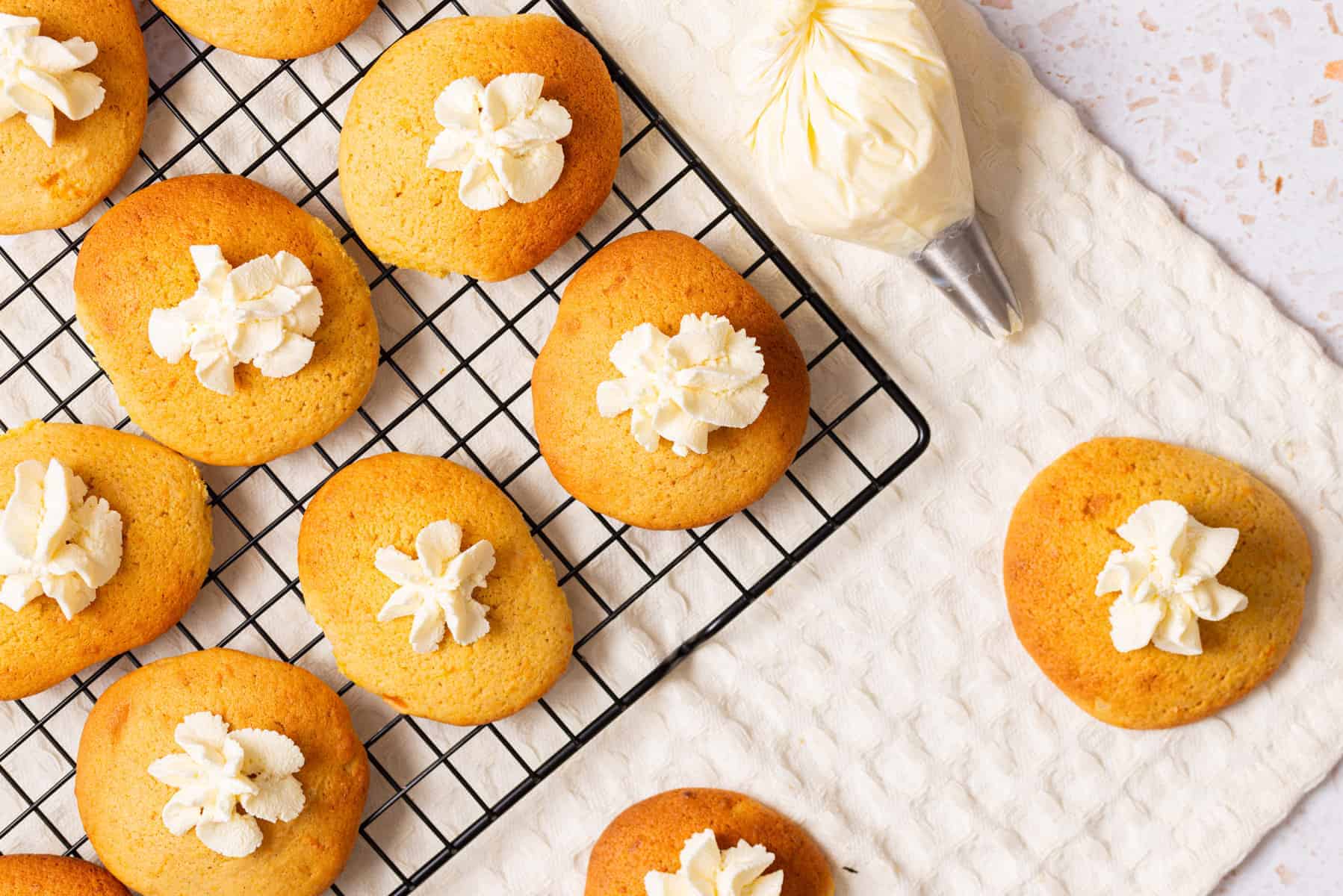 An overhead image of pumpkin pie cookies with whipped cream on top cooled on a wire rack.