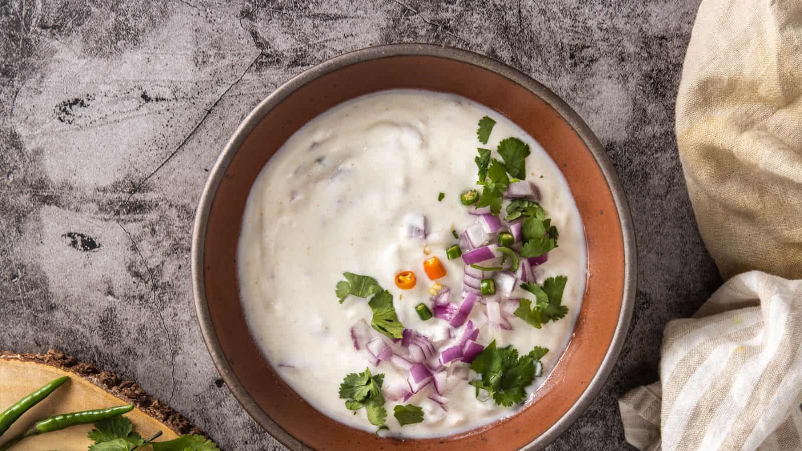 An overhead view of homemade raita served in a brown bowl.