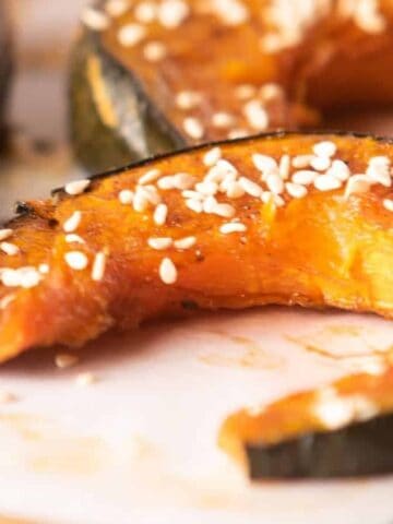 Close-up of baked kabocha squash slices seasoned with sesame seeds.