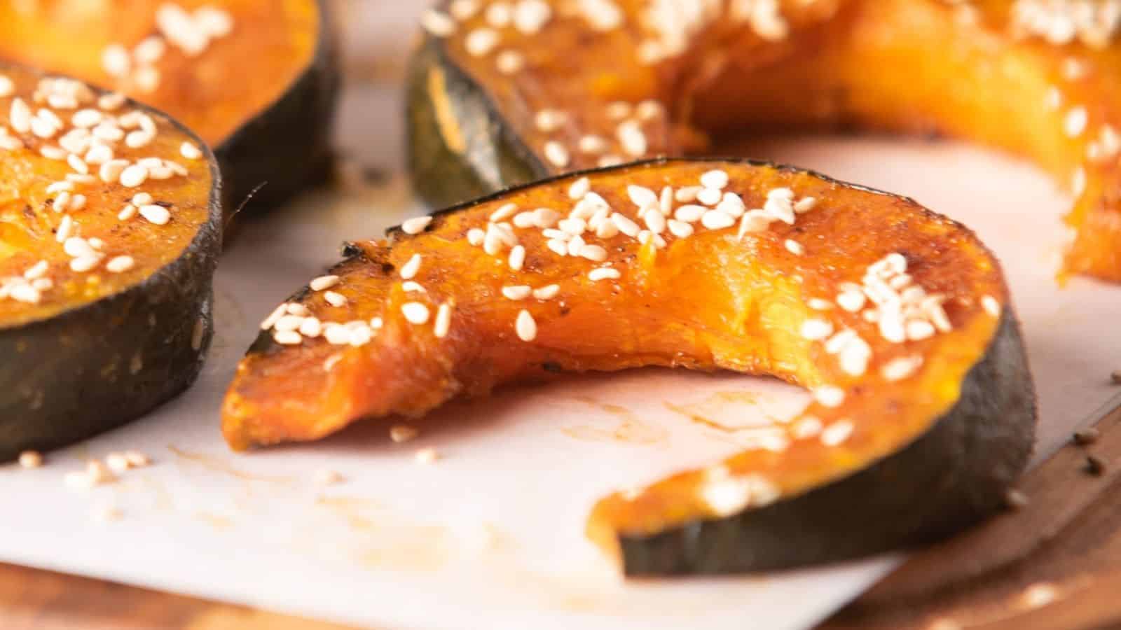 Close-up of baked kabocha squash slices seasoned with sesame seeds.