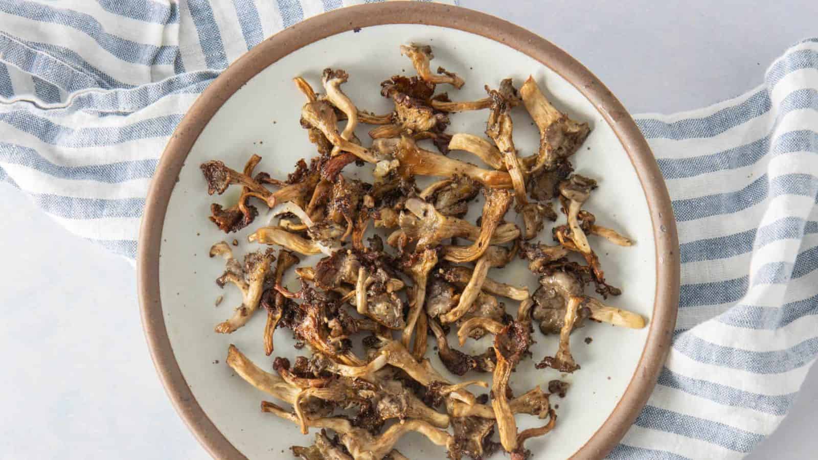 A close up image of roasted oyster mushrooms placed in a plate over a napkin.