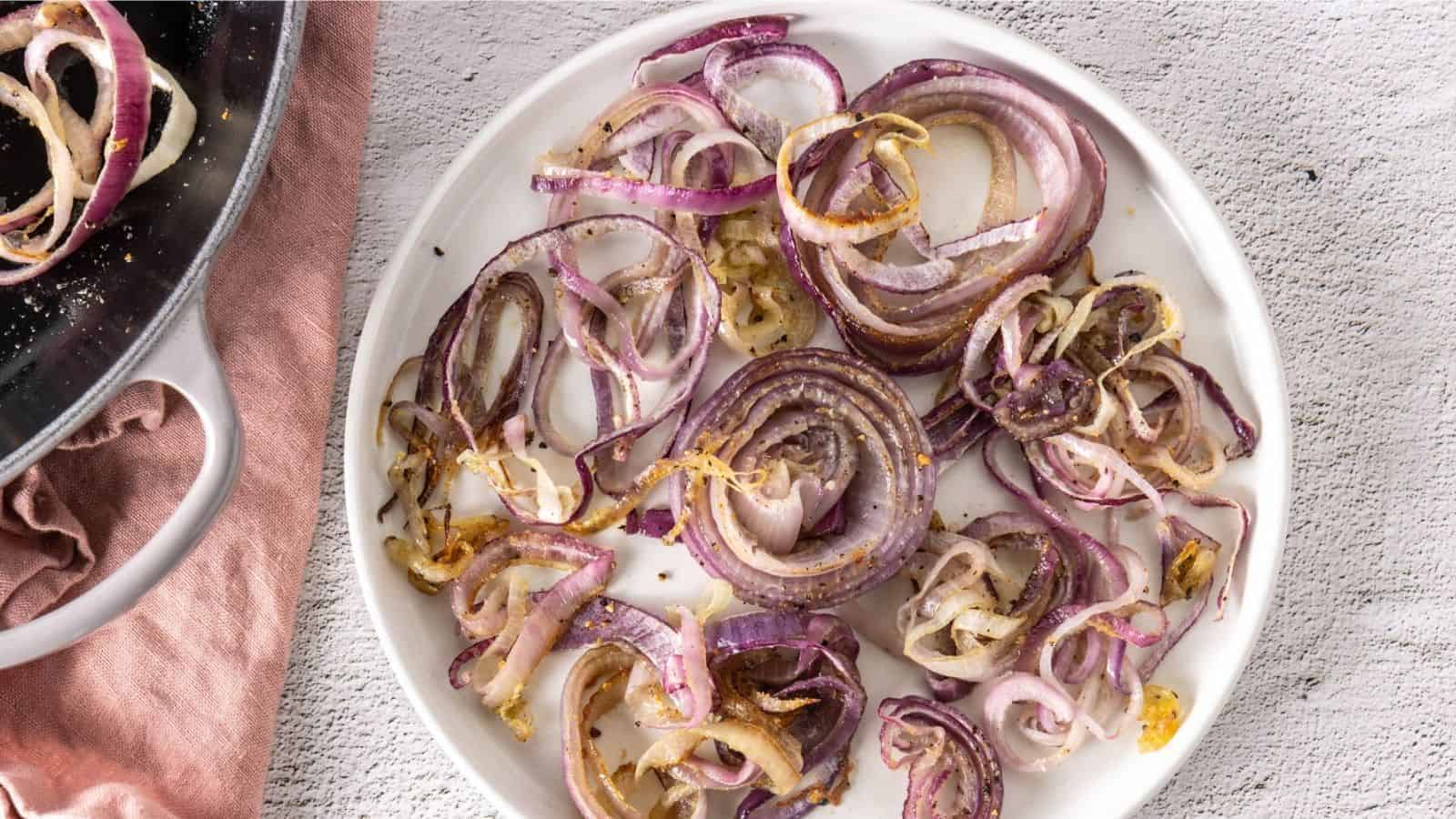 An overhead image of roasted red onions in a white plate.