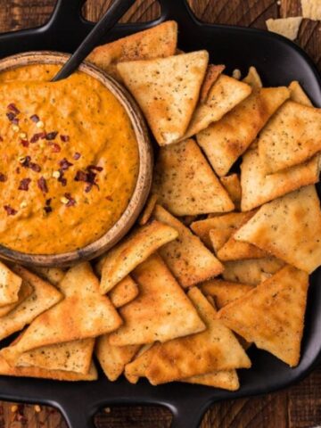 Overhead view of roasted red pepper cream cheese dip in a bowl with biscuits.