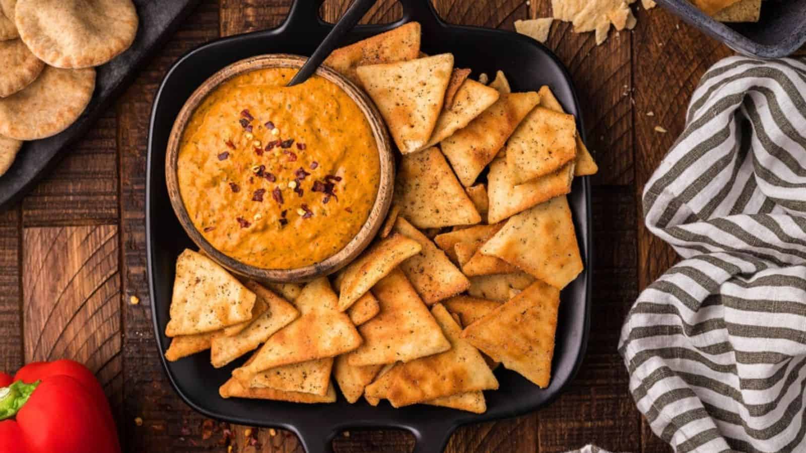Overhead view of roasted red pepper cream cheese dip in a bowl with biscuits.