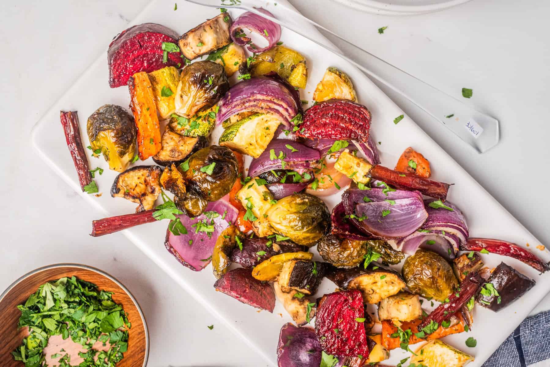 An overhead image of roasted vegetable salad on a serving dish. with the dressing on the side.