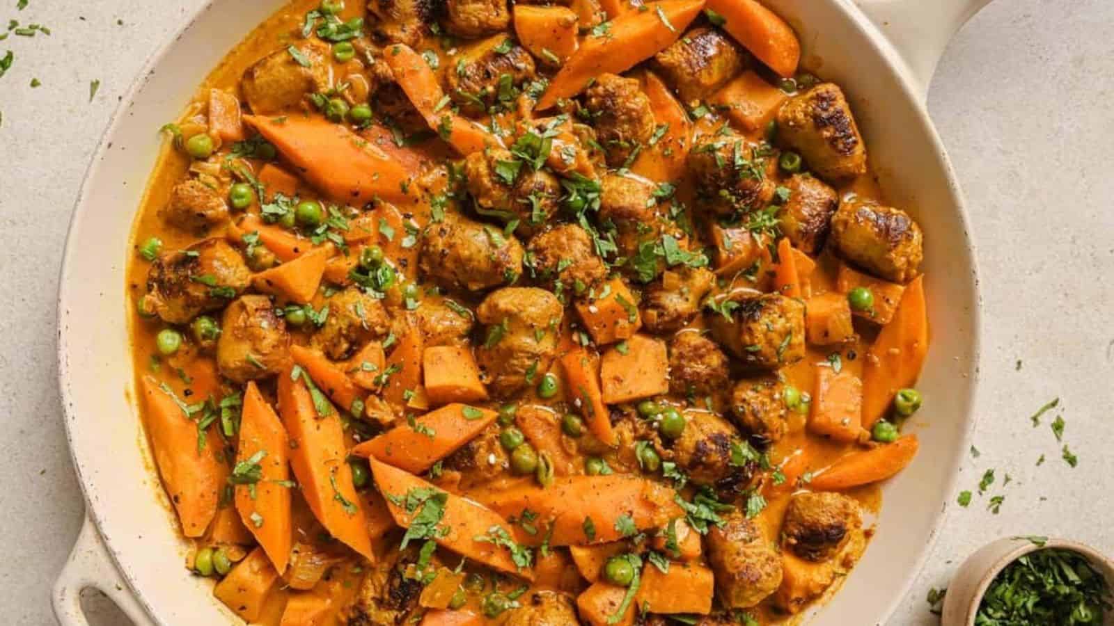 Sausage curry in a skillet garnished with herbs.