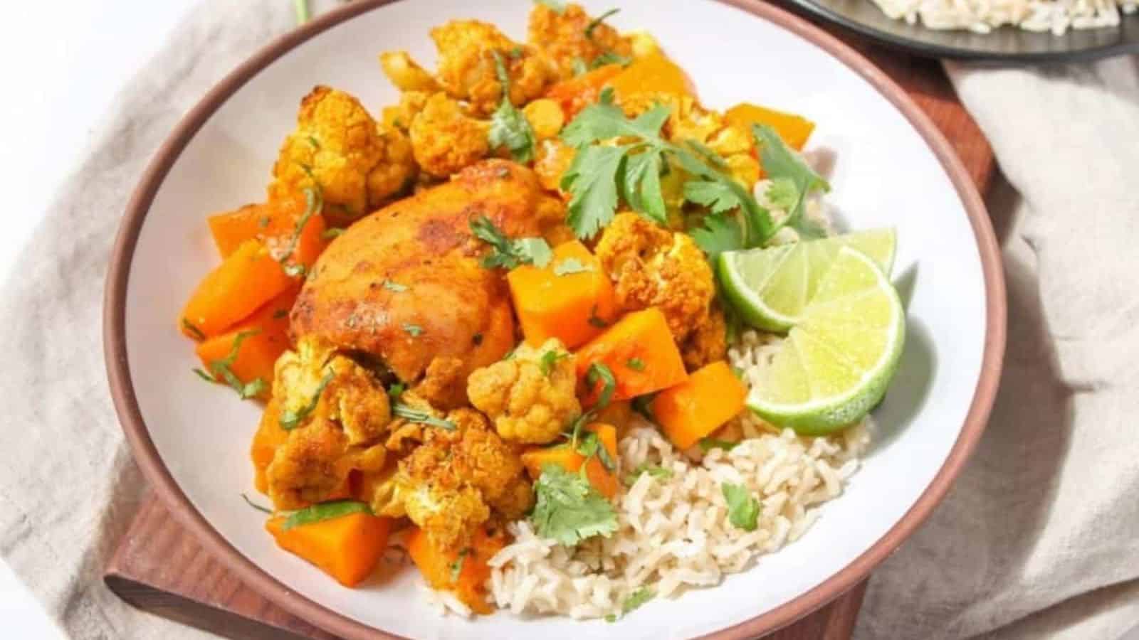 Roasted chicken thighs with butternut squash, cauliflower, and rice on a plate.