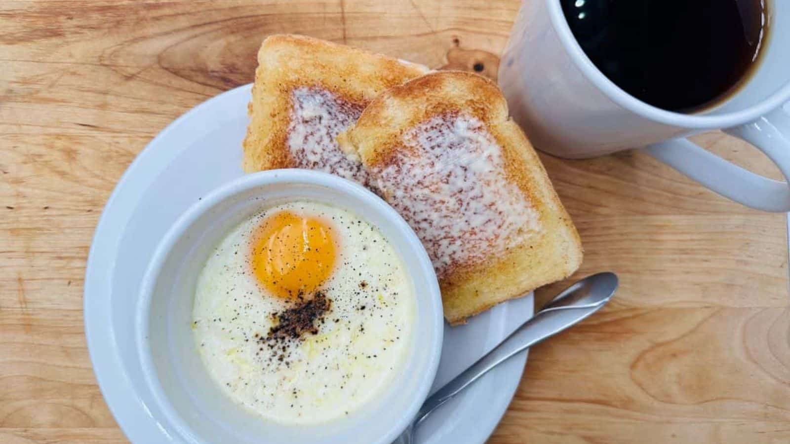 A cup of coffee and an egg on a plate.