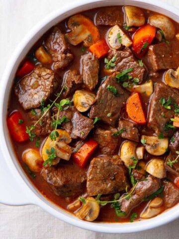 A picture of beef stew with mushrooms carrots and thyme.