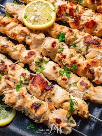 Chicken skewers with lemon wedges on skewers.